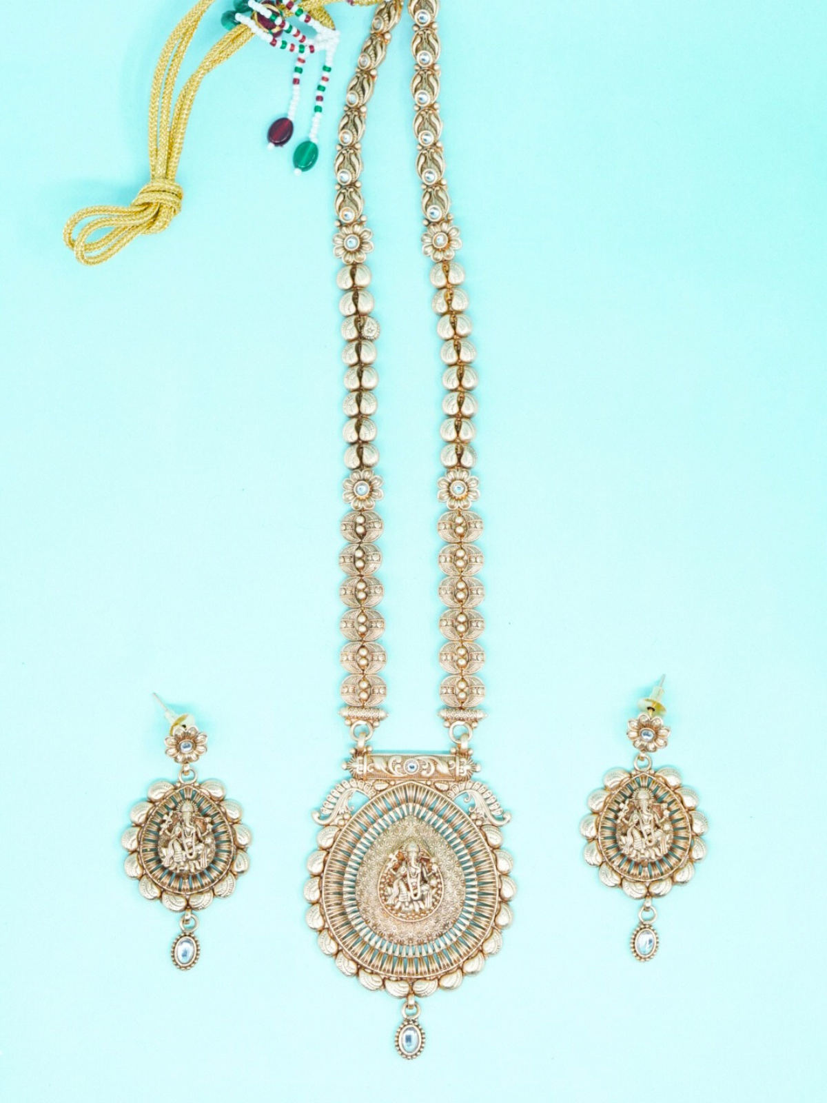 Antique gold temple necklace set with Lord Ganesha pendant and matching jhumka earrings displayed top view