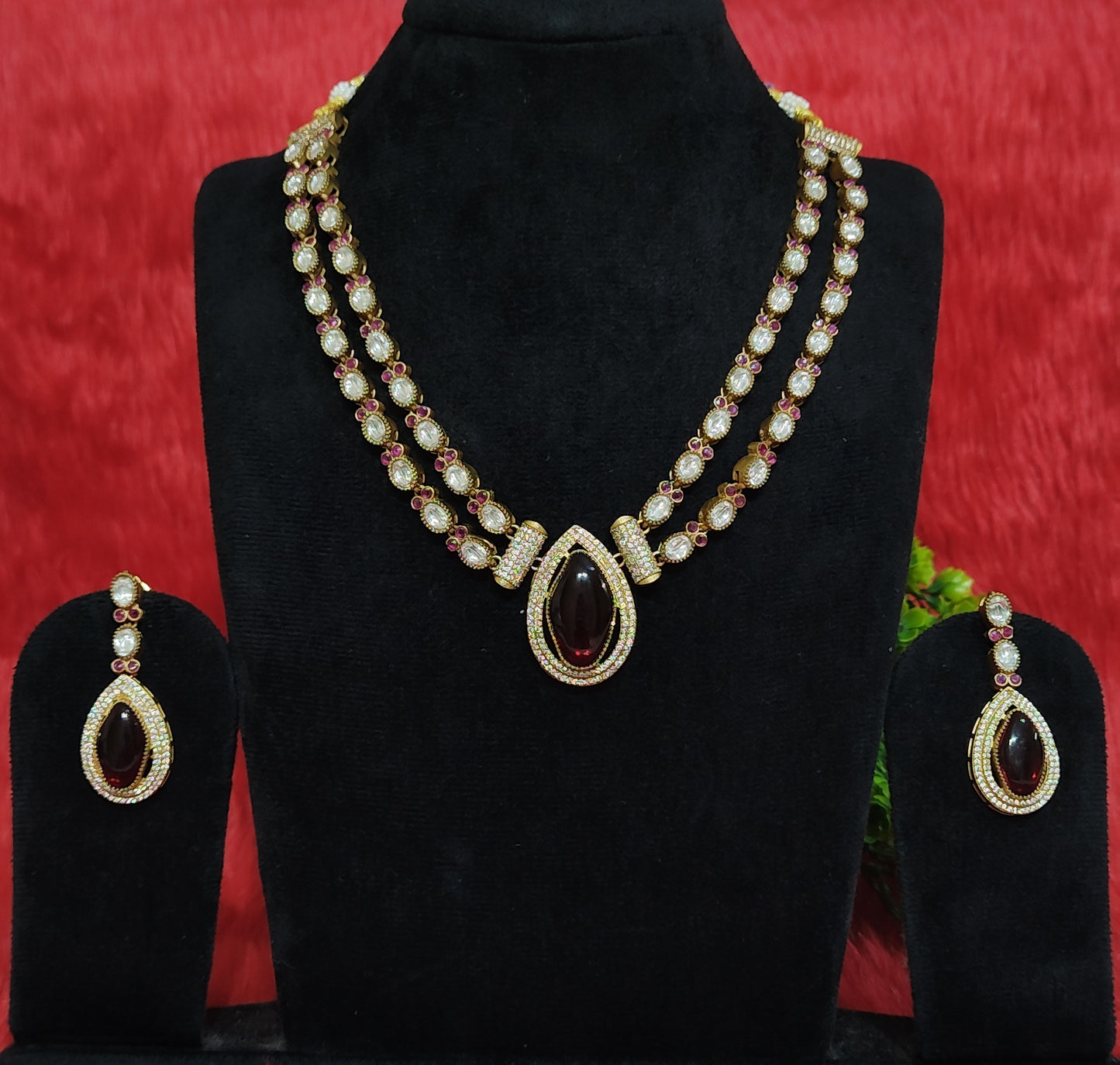 Premium kundan necklace set with twin-layer chain, maroon masonite pendant, and matching earrings displayed on black stand