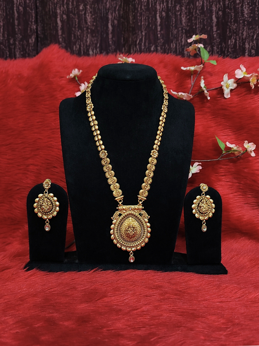 Antique gold temple necklace set with Lord Ganesha pendant and matching jhumka earrings displayed on black stand