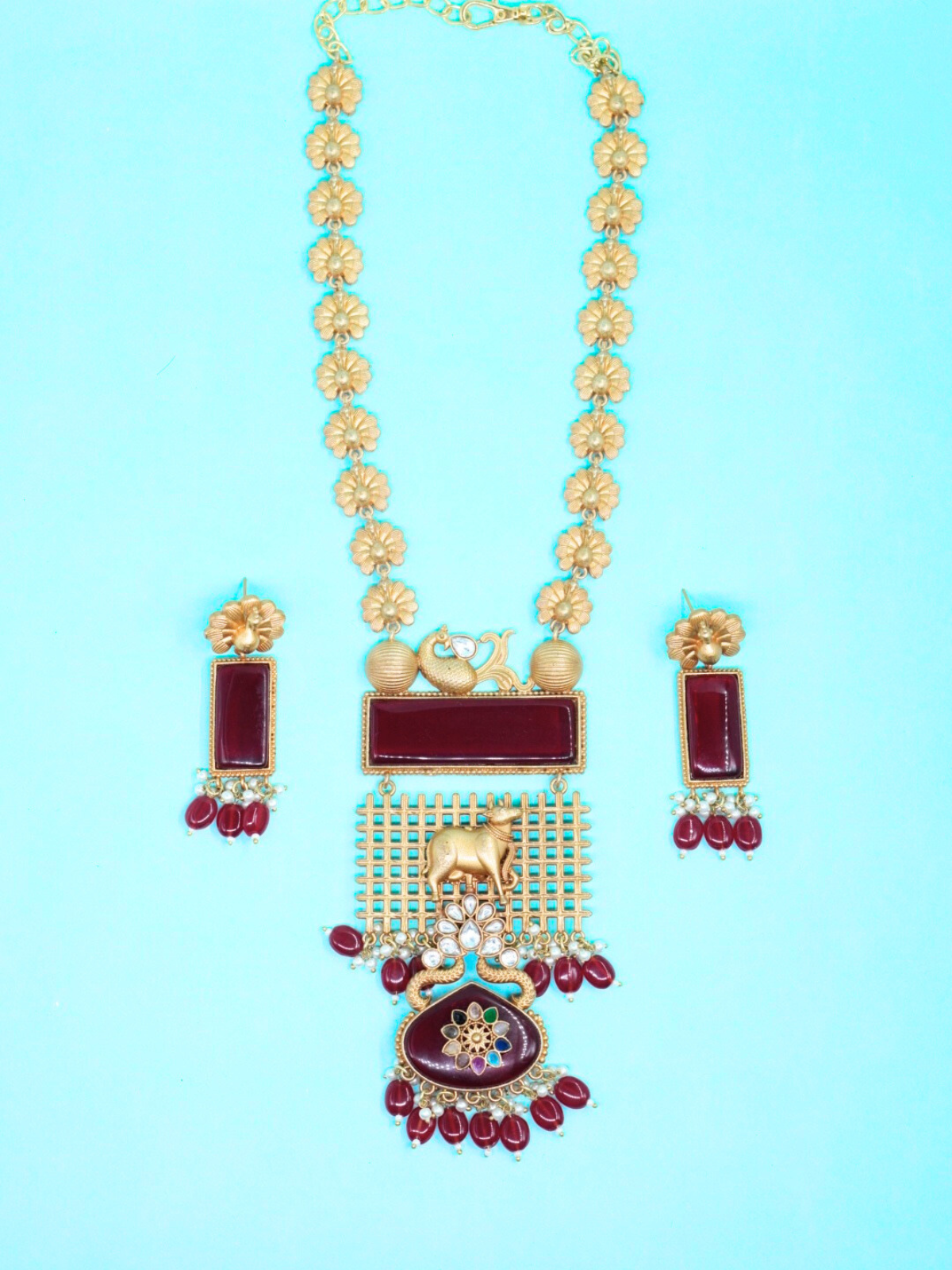 Apala Long State red stone temple necklace set with cow motif and matching earrings on blue background