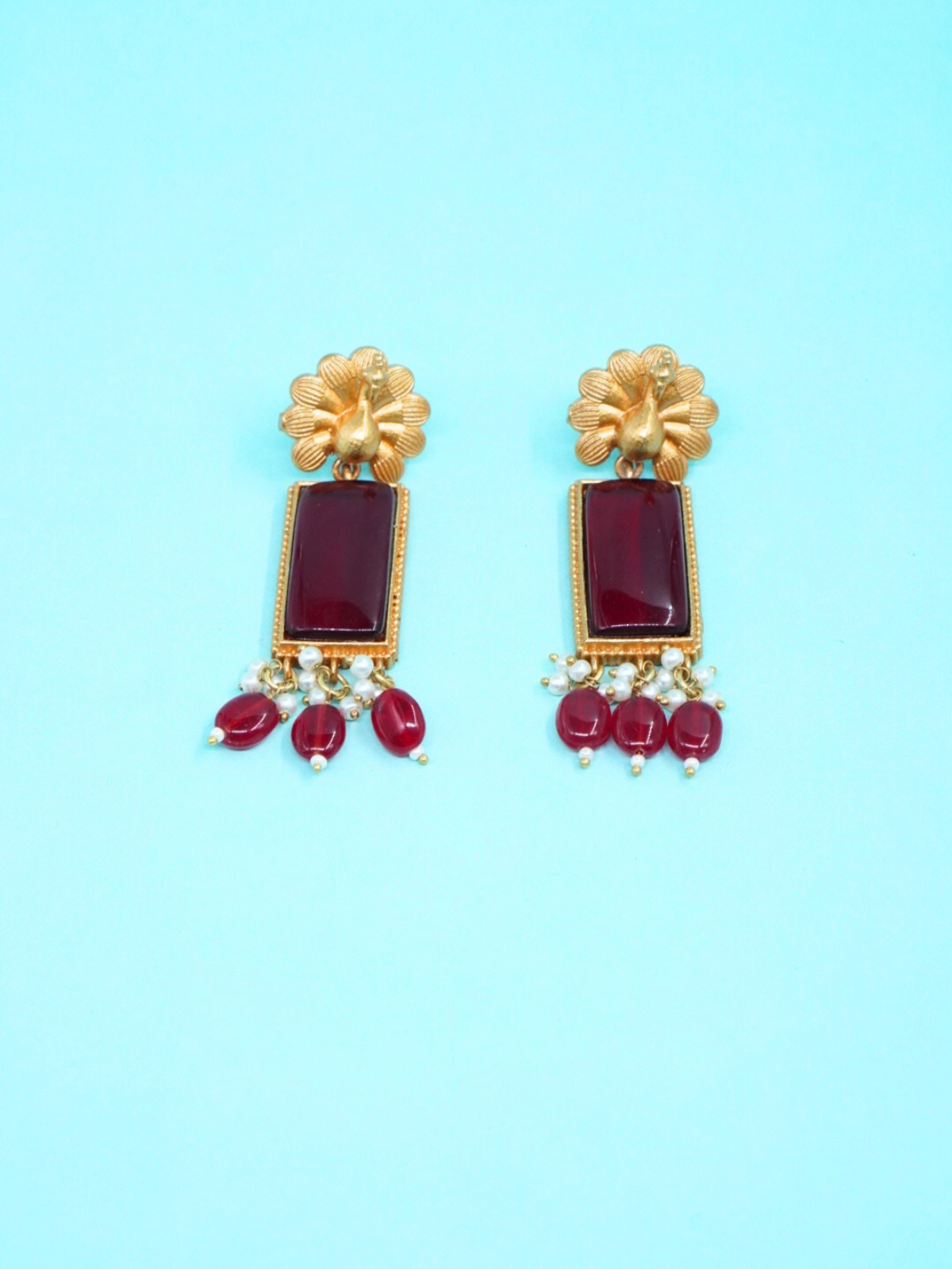 Apala red stone temple earrings on blue background