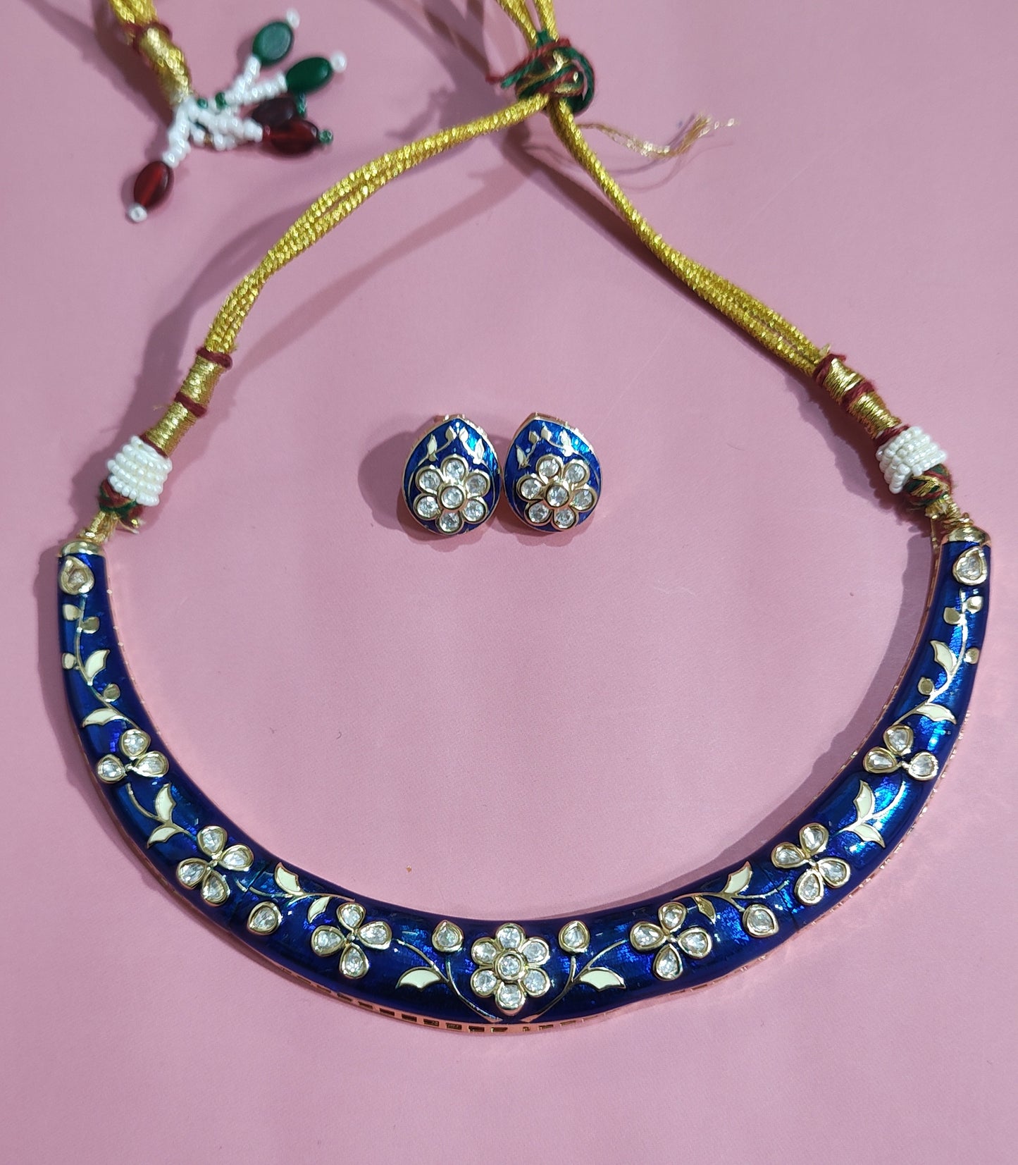 Blue meenakari necklace set with kundan floral designs and matching stud earrings displayed close-up