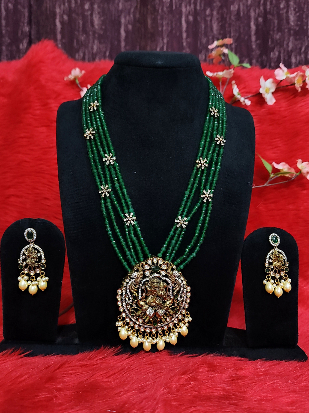 Green beaded temple necklace set with Lakshmi pendant and pearl earrings on dummy