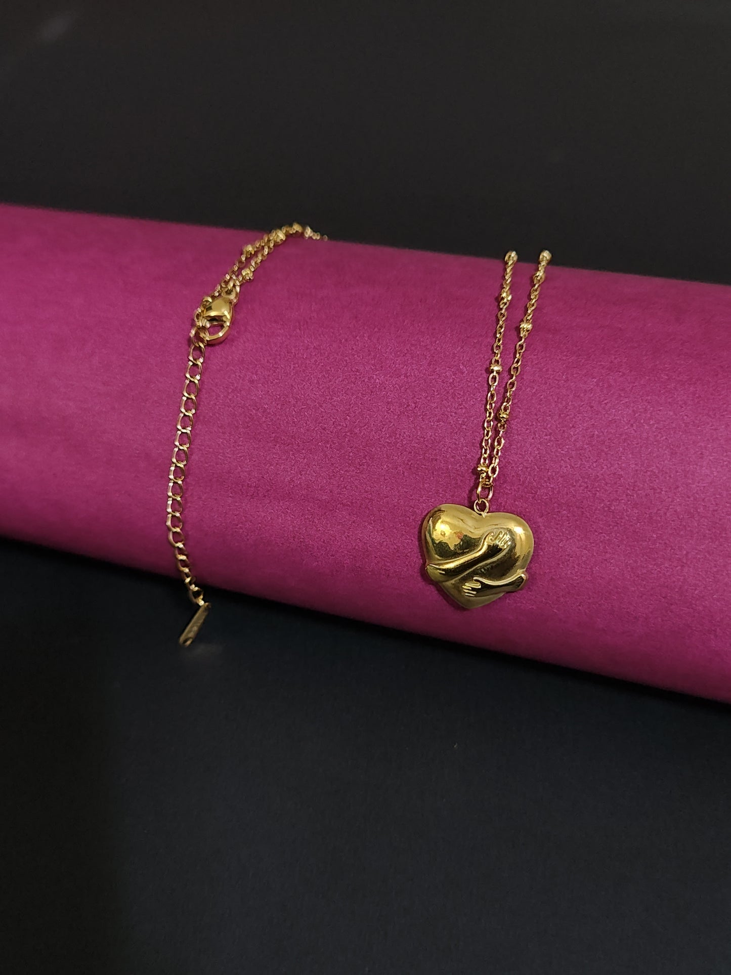 Anti-tarnish heart charm necklace with embracing hands design.