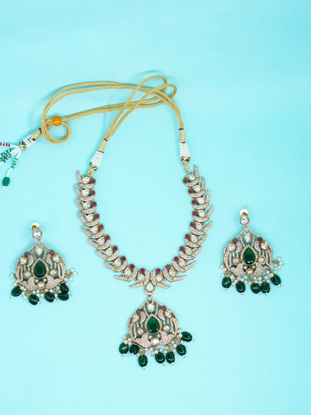 Moissanite stone necklace set with green drop beads and matching earrings on blue background