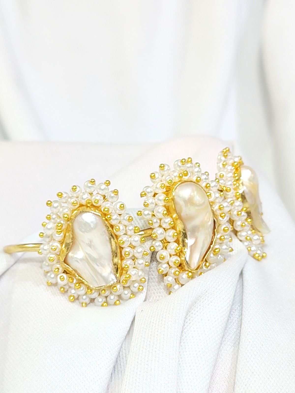 Mother of Pearl bracelet in brass with pearl beading close view on white background