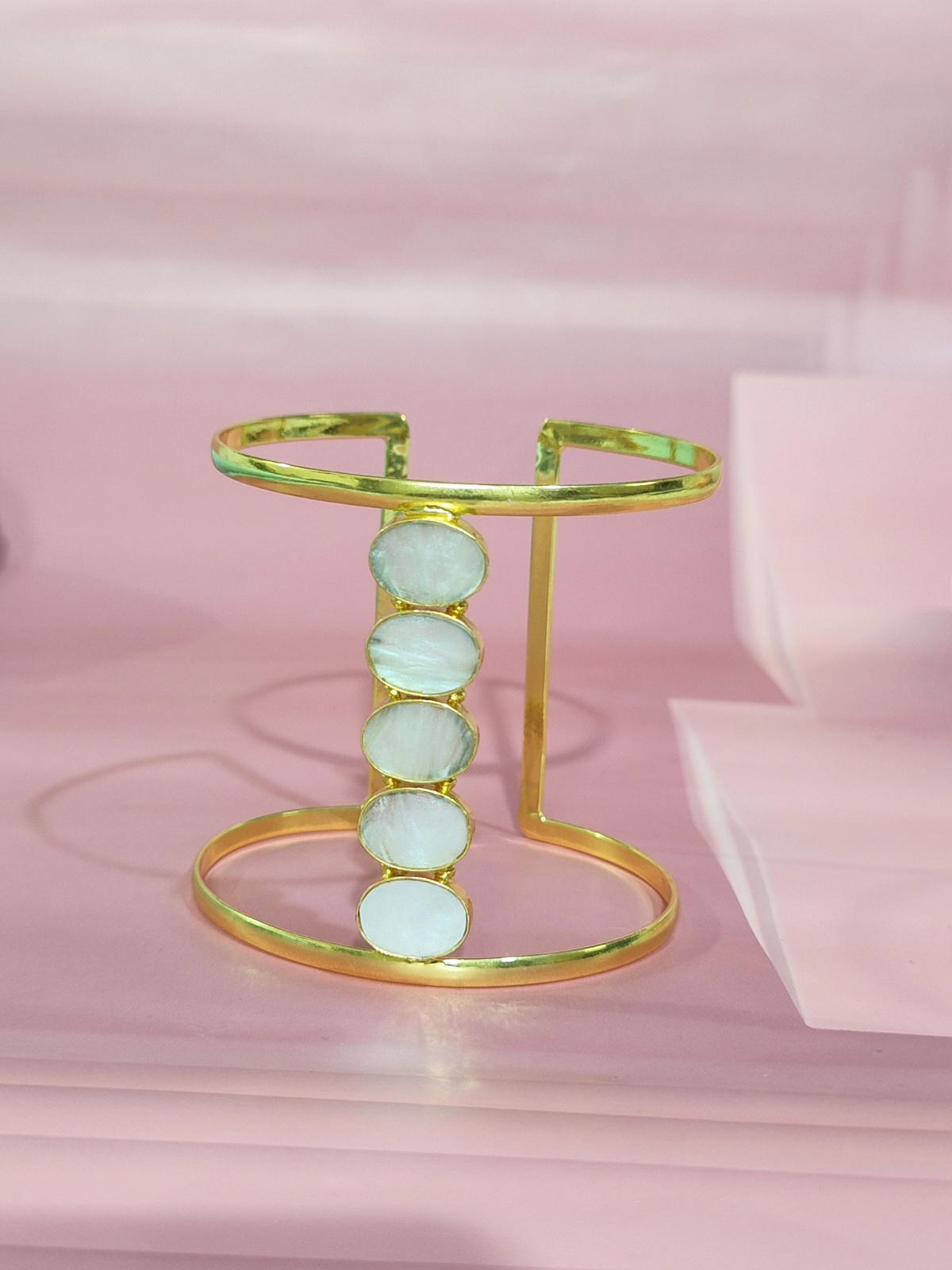 Mother of Pearl cuff bracelet in brass on pink background