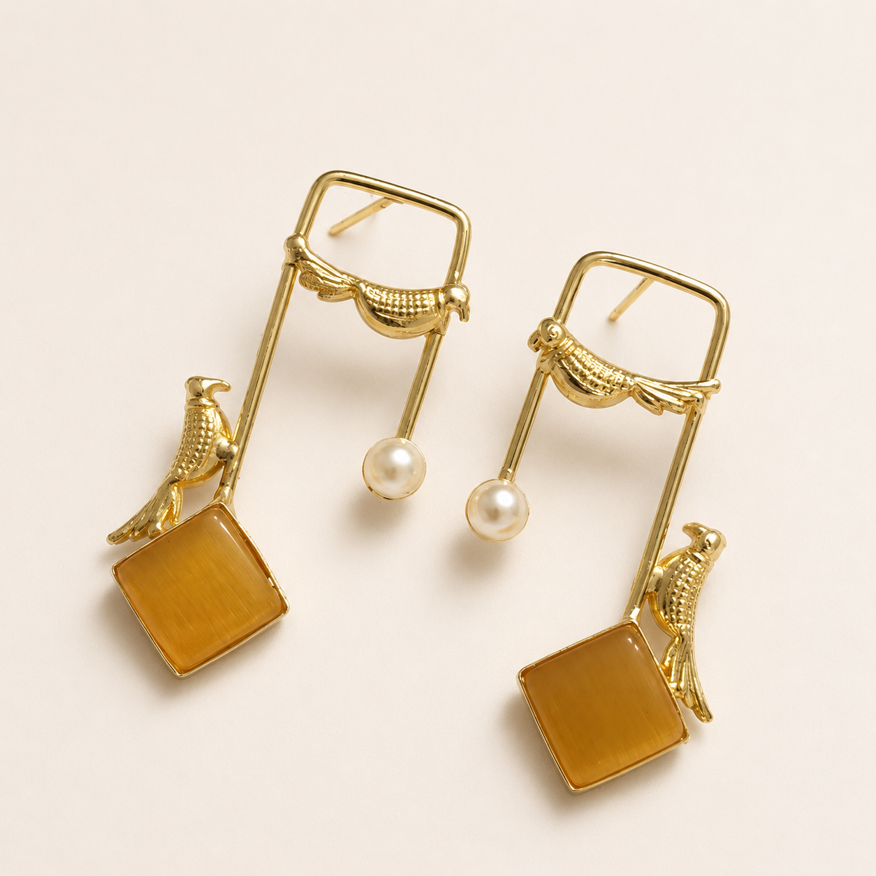 Amber brass bird and artificial pearl statement earrings on ivory
