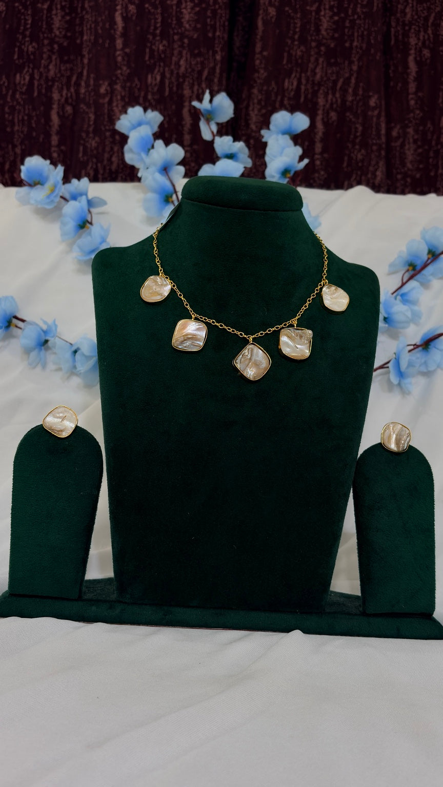 Brass mother-of-pearl five-drop necklace with matching stud earrings on green bust