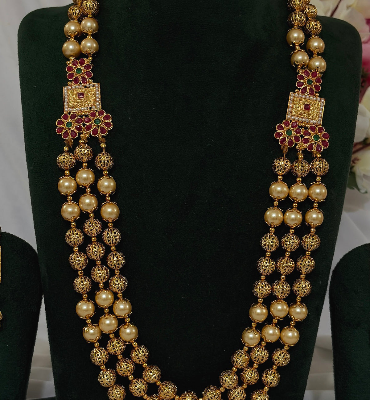 Close-up of copper-finish Matar Mala necklace with filigree beads and red and green floral details