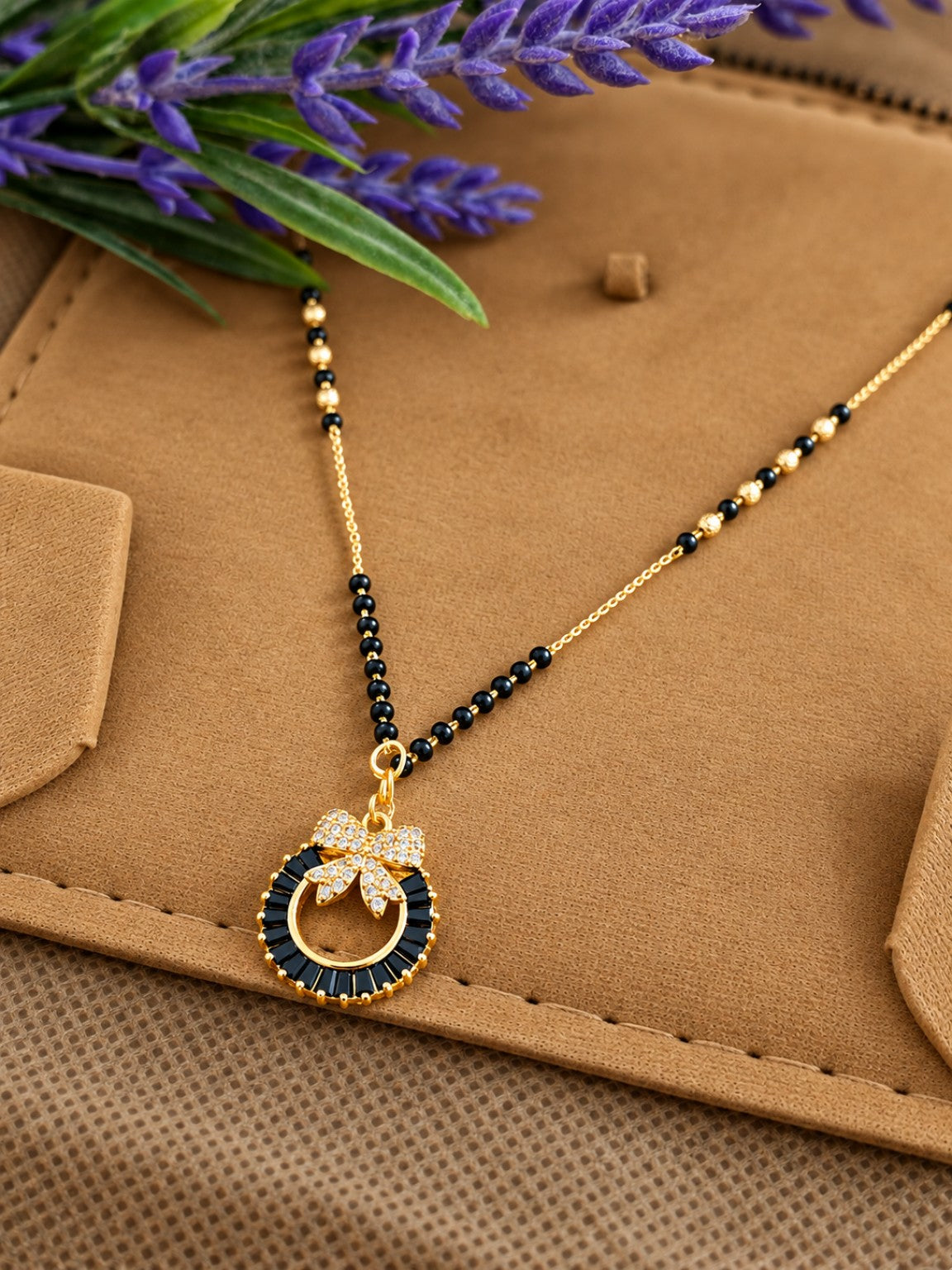 Micro gold-plated black bead mangalsutra with black stone circular pendant and crystal bow detail