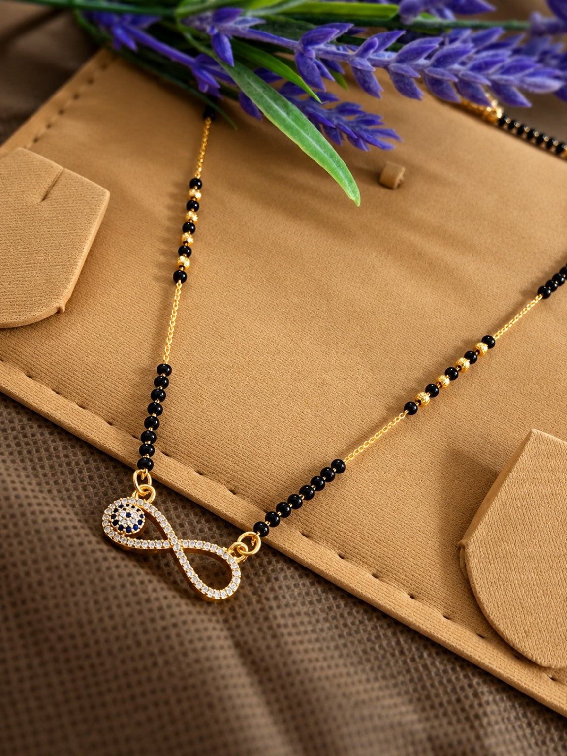 Micro gold-plated black bead mangalsutra with infinity pendant and blue evil eye stone detail