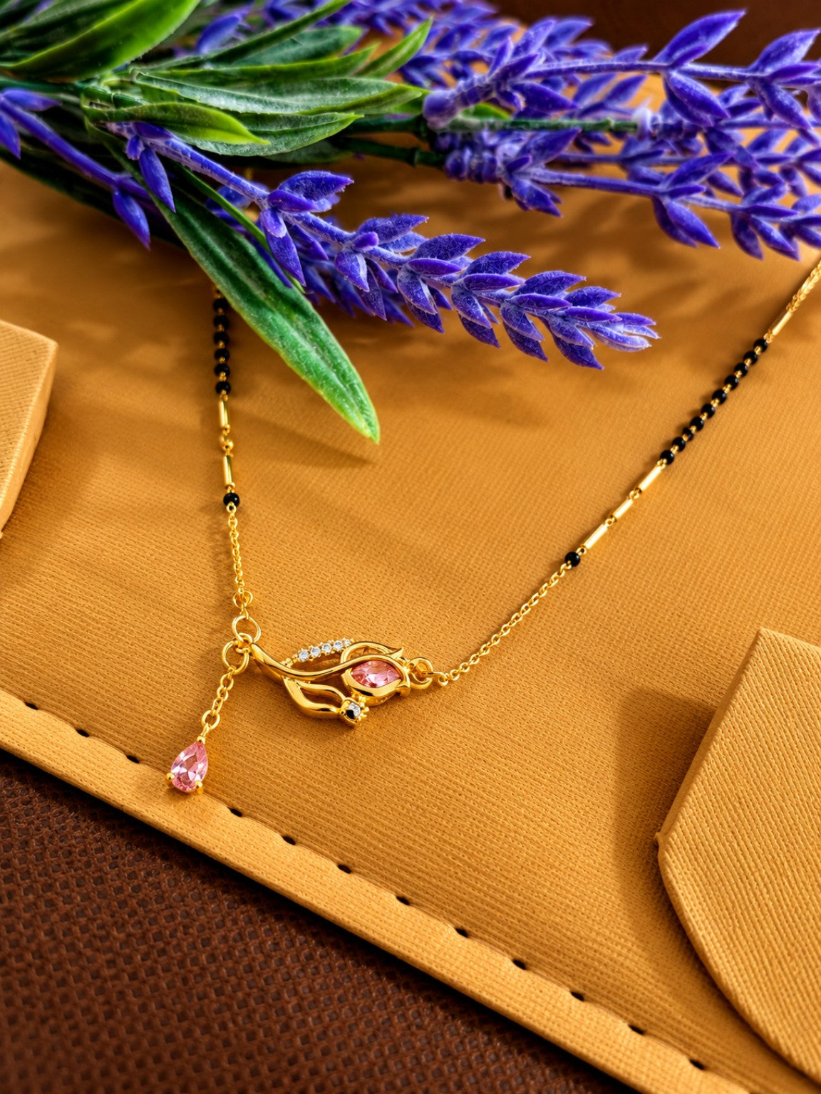 Micro gold-plated black bead mangalsutra with pink teardrop stone and elegant swirl pendant