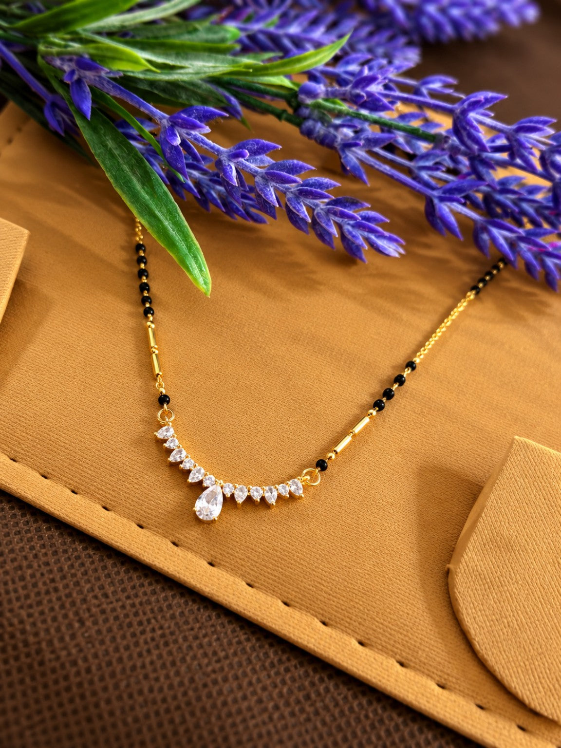 Micro gold-plated black bead mangalsutra with curved crystal fan pendant and teardrop centre stone