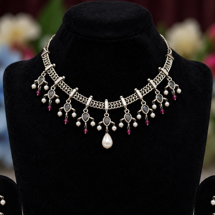 Close-up of oxidised silver replica necklace with black stones, pearl accents and pink bead drops