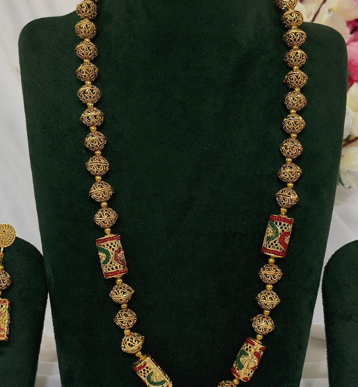 Close-up of South Indian Matar Mala necklace with filigree beads and red and green enamel-style details